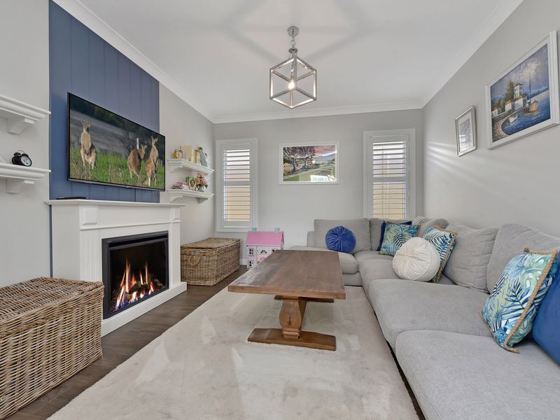 Spacious living room with long sofa, stylish table, and cozy firepit.