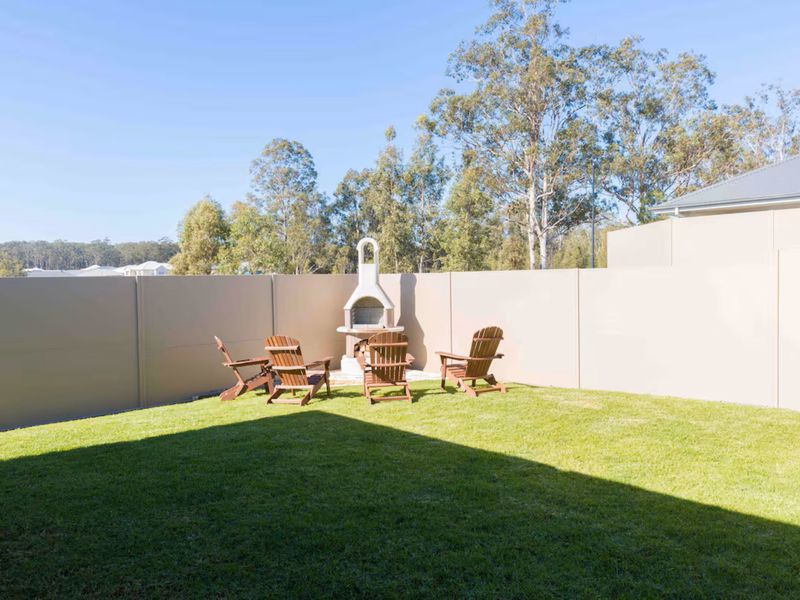 Outdoor fireplace setting with chairs and a large open lawn.