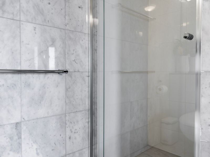 Walk in shower with sleek tiled interior and clean, modern design