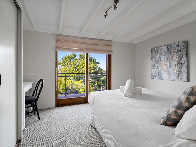 Wake up in a bright bedroom framed by expansive windows and scenic views.