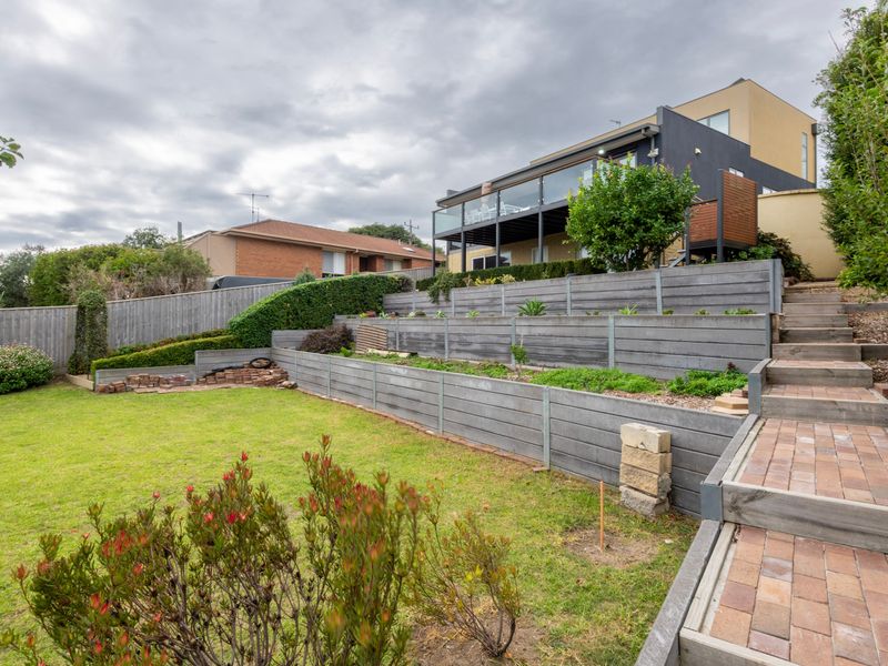 Spacious rear lawn surrounded by established greenery.