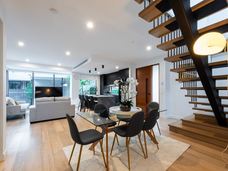 Open-plan dining and living area with furnishings and striking floating staircase