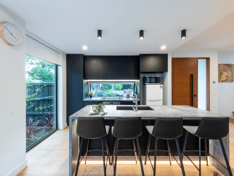 Modern entertainer’s kitchen with breakfast bar, sleek finishes and garden outlook