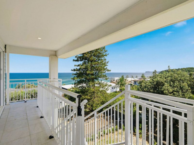 Covered balcony with sweeping ocean and treetop views.