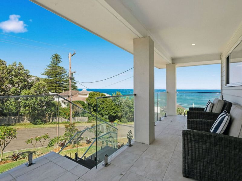 Covered balcony with outdoor seating and ocean views.