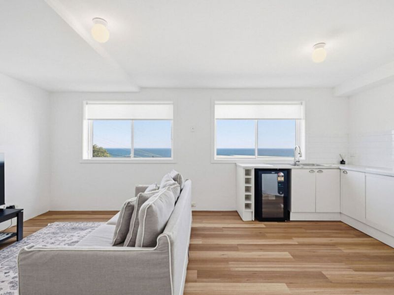 Bright open-plan living area with kitchenette and ocean glimpses.