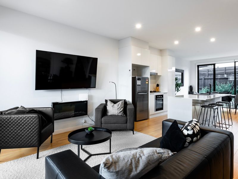 Relax in the light-filled living room with a smart TV, plush seating, and seamless indoor-outdoor flow.