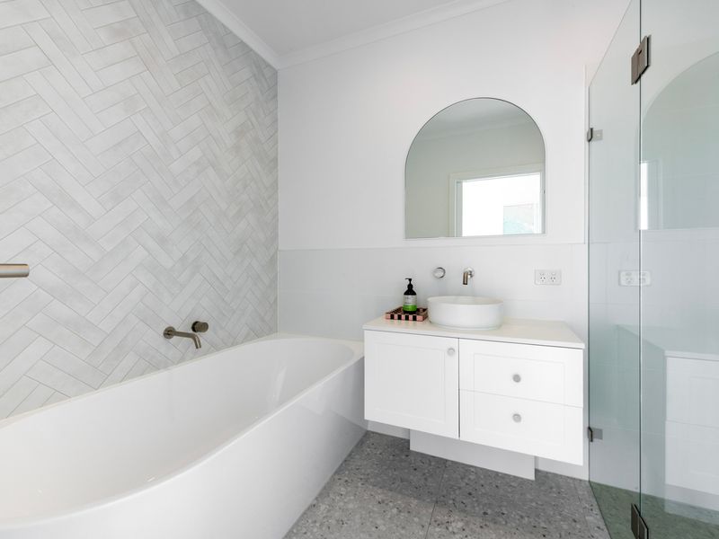 The modern family bathroom features a full-size bathtub and elegant contemporary finishes.
