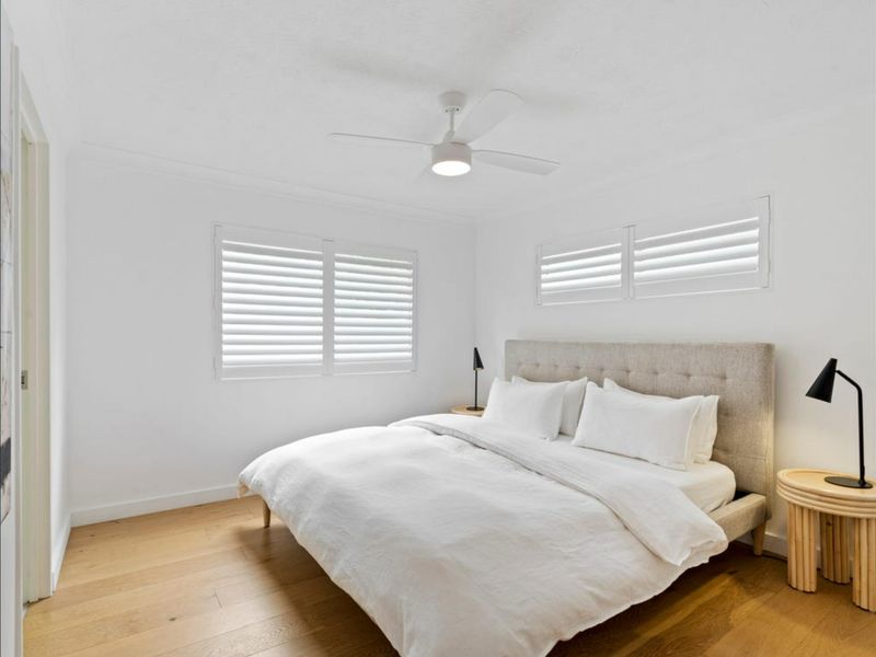 Wake up refreshed in the peaceful master bedroom featuring plush bedding and plantation shutters.
