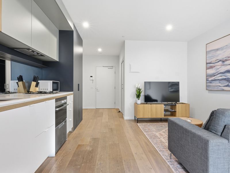 The sleek open-plan layout blends the kitchen, living, and dining areas into one stylish space.