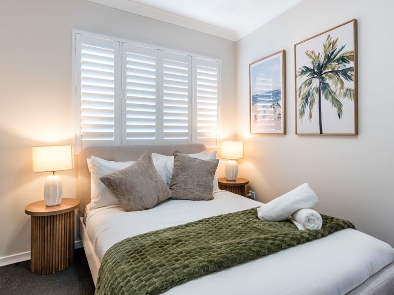 Peaceful bedroom with plantation shutters and soft furnishings.