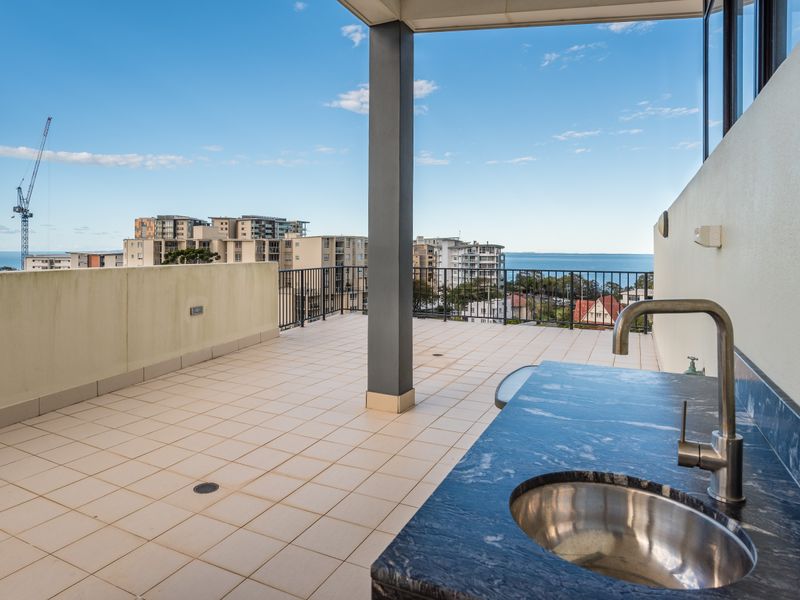 Expansive rooftop terrace with BBQ and water glimpses.