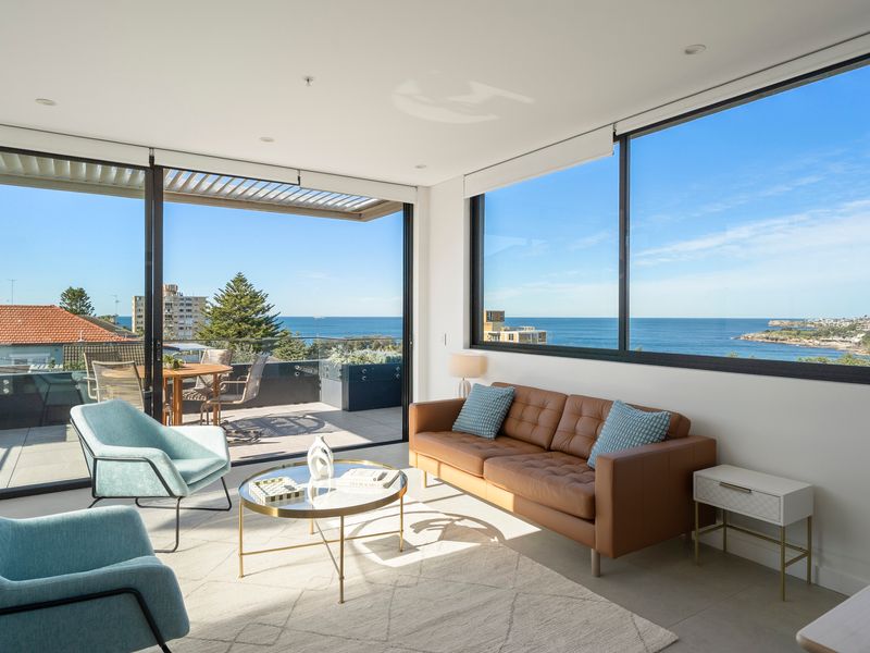 Floor-to-ceiling windows frame breathtaking ocean views from the private balcony.
