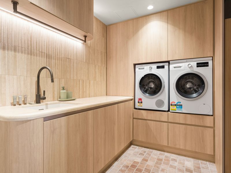 Full laundry with washer, dryer, custom cabinetry, and folding area.