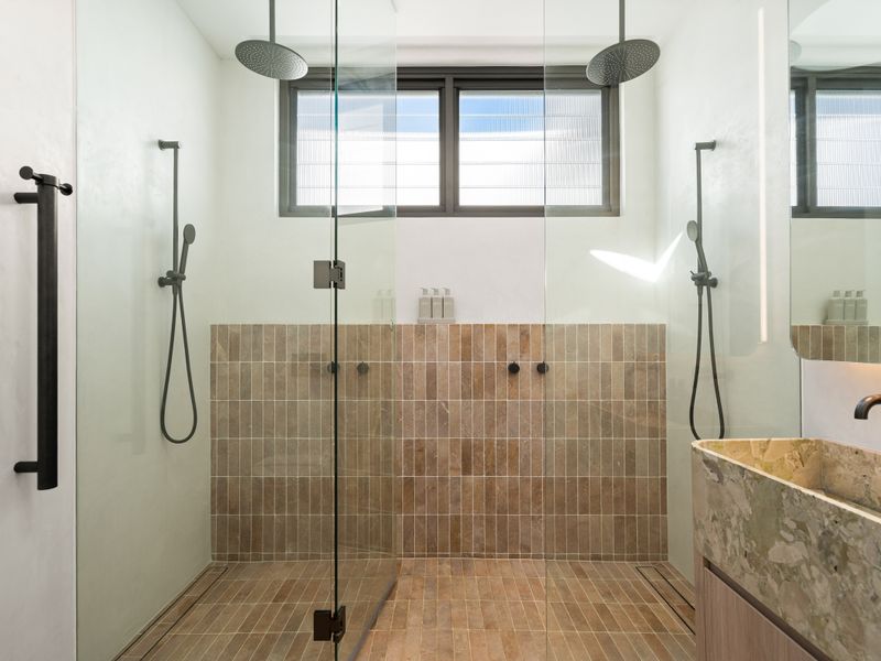Walk-in shower with minimalist black fittings and contemporary styling.