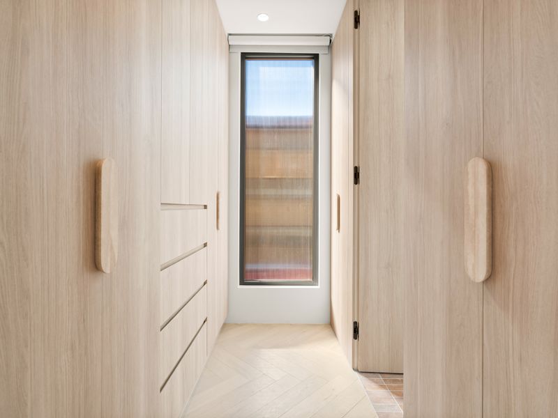 Light-filled hallway framed by custom cabinetry and a feature entry door.