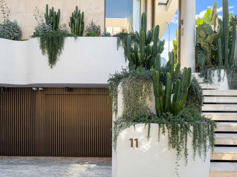 Private entrance framed by architectural greenery and secure garage.