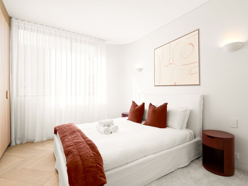 Peaceful bedroom with plush bedding and warm timber finishes.
