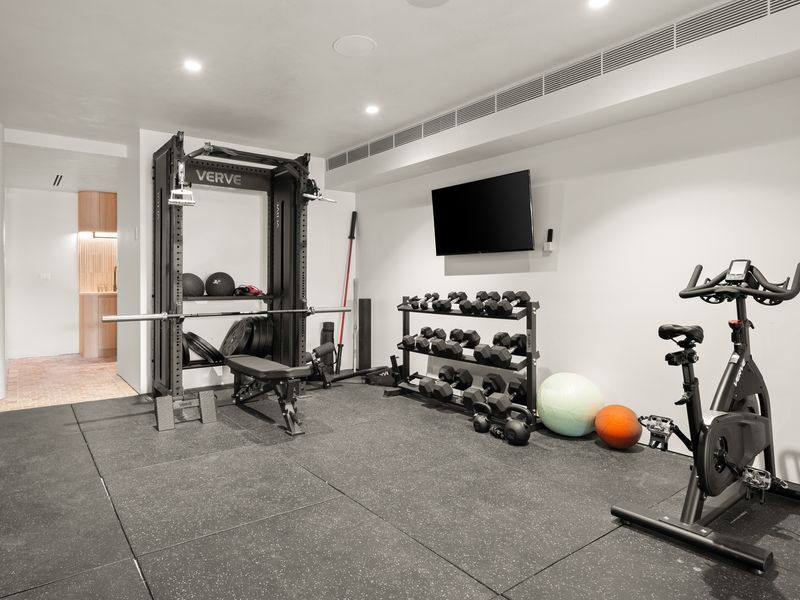 Private fitness room equipped with weights, cardio equipment, and a TV.