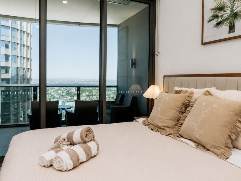 Plush bedroom with floor-to-ceiling windows and balcony access.