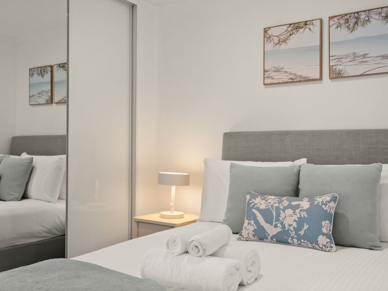 Queen bed with mirrored wardrobe and bedside lighting.