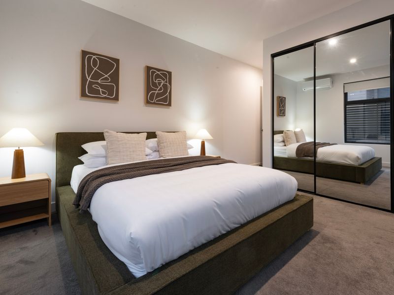 Primary bedroom featuring a queen bed, ensuite and mirrored built-in wardrobes.