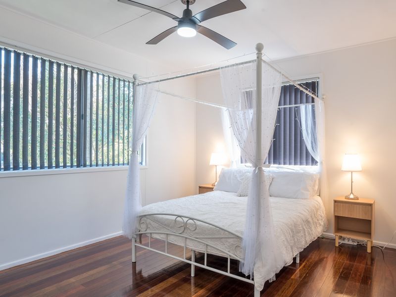 Bright bedroom with ceiling fan and large window for natural light.