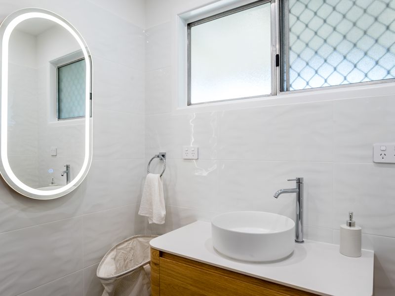 Contemporary bathroom with an illuminated mirror and sleek vanity.