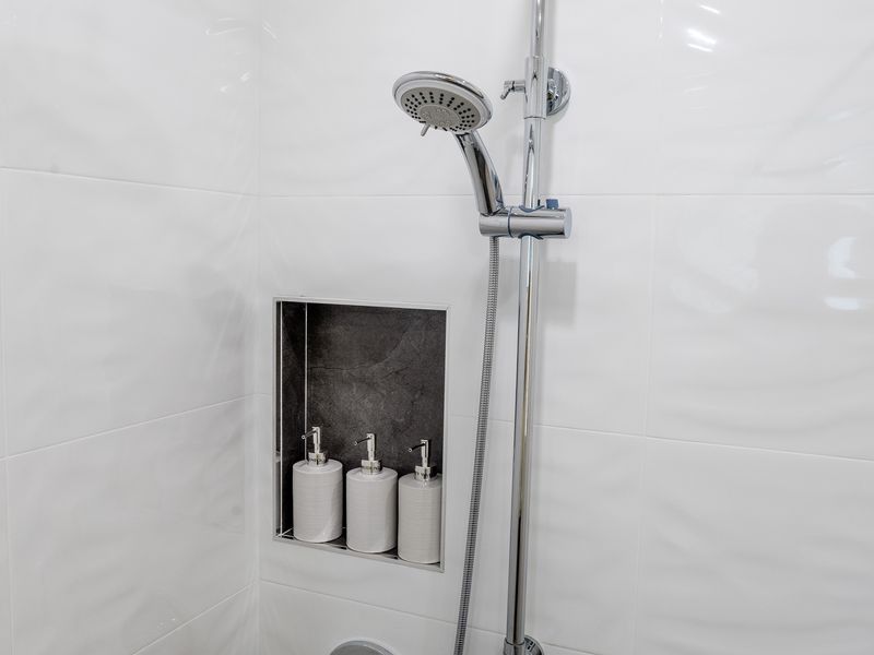Walk-in shower featuring a recessed niche stocked with toiletries.