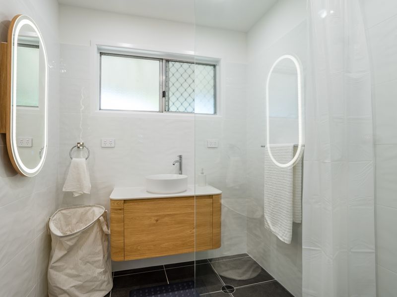 Modern bathroom with a timber vanity and LED mirrors.