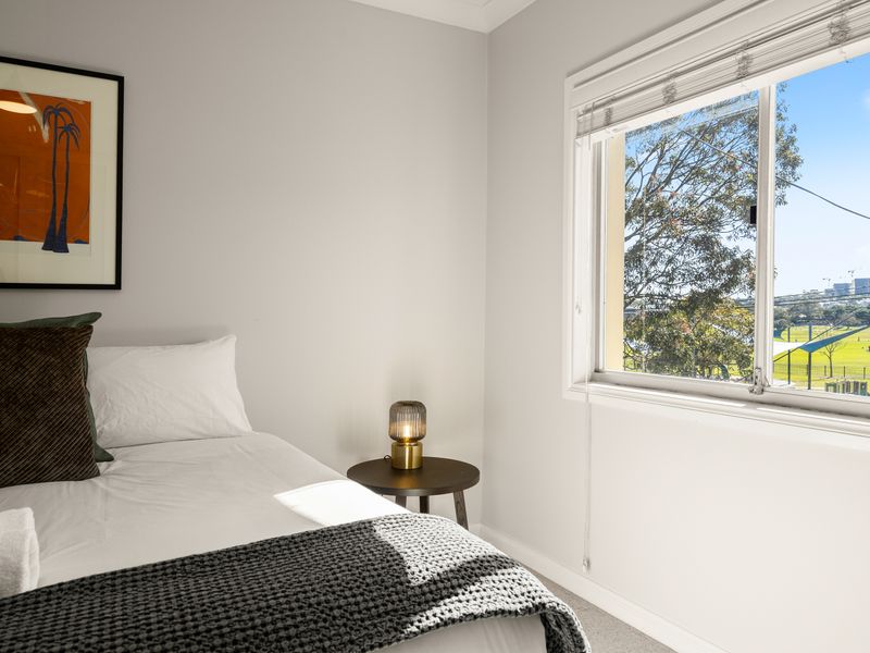 Peaceful bedroom with lovely park views through large windows.