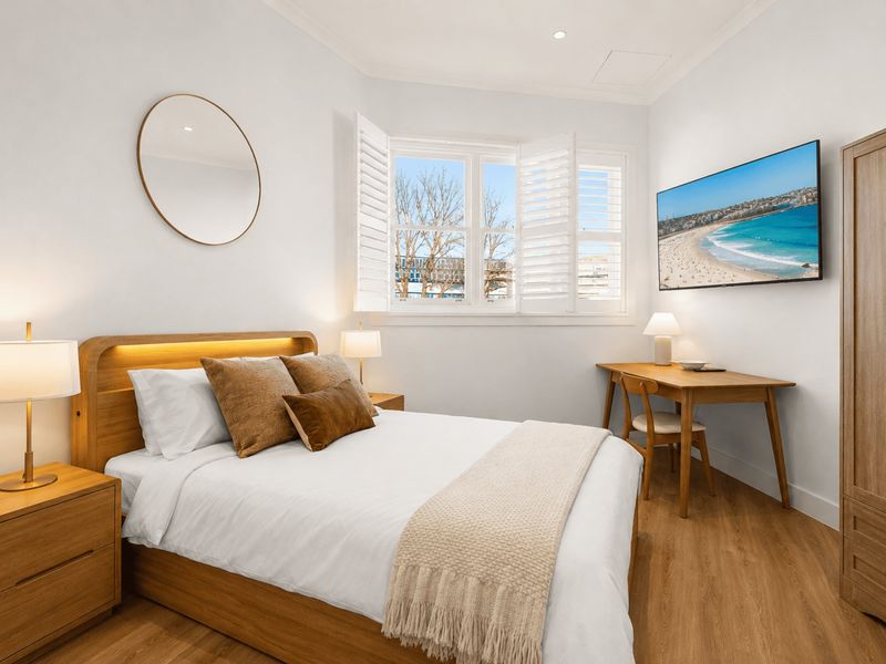 Bright and inviting bedroom with a comfortable queen bed and plantation shutters.