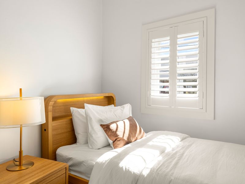 Peaceful bedroom with plenty of natural light and built-in storage.