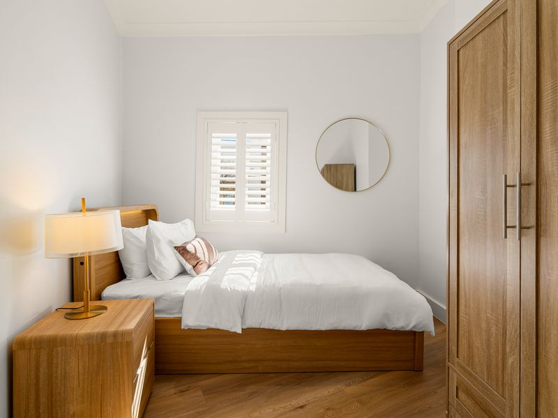 Another view of the stylish bedroom with bedside lighting and seating area.
