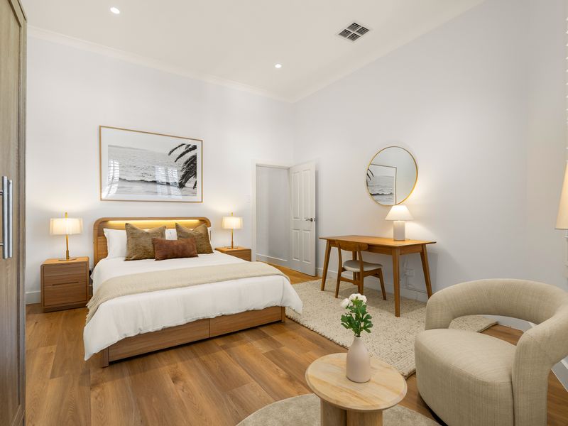 Spacious bedroom featuring a queen bed, armchair and wardrobe.
