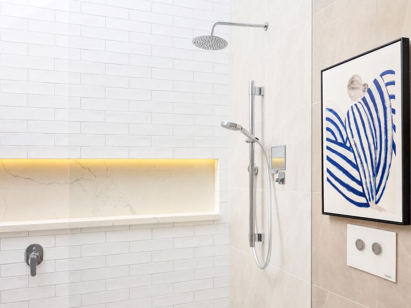 Sleek walk-in shower with ambient lighting and abstract art.