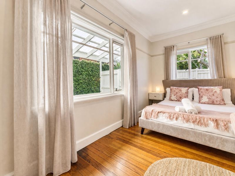 Warm and inviting guest bedroom with soft pink accents and sheer curtains.
