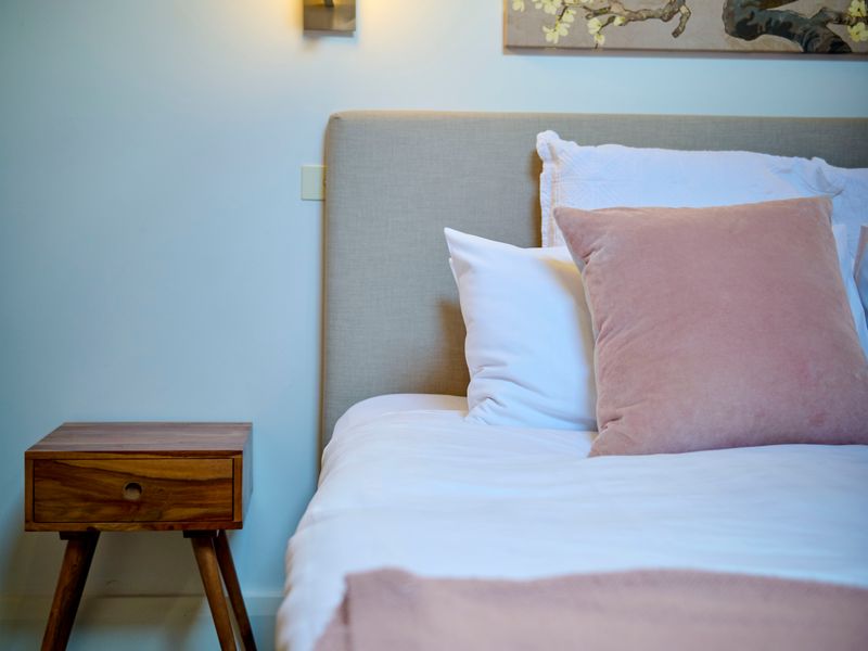 Comfortable bedroom with soft pink accents and warm lighting.