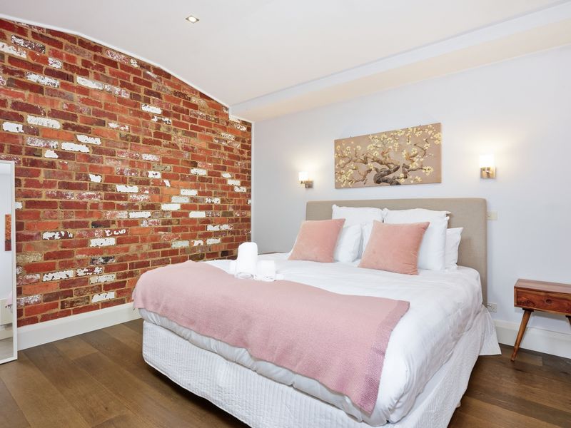 Comfortable bedroom with soft pink accents and warm lighting.