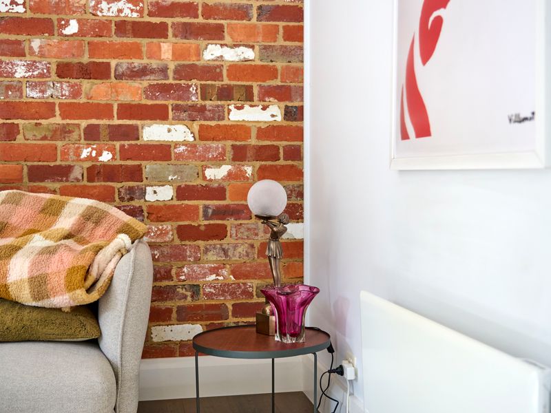 Cozy corner with an exposed brick wall and warm throw blanket.