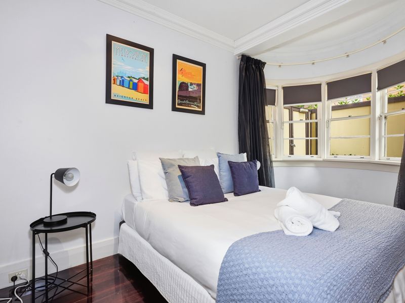 Cozy guest bedroom featuring blue accents and large bay windows.