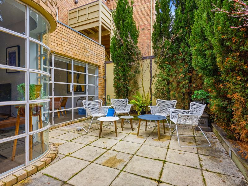 Charming private patio area surrounded by lush greenery and outdoor seating.