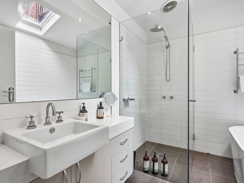 Modern bathroom with a glass-enclosed shower and white tiling.