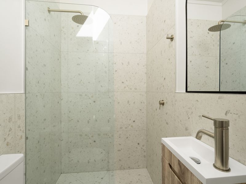 Modern glass-enclosed shower stall with clean white tiling.