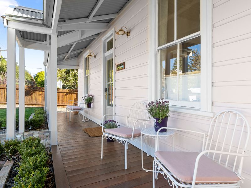 Covered veranda featuring white railings and outdoor seating chairs.