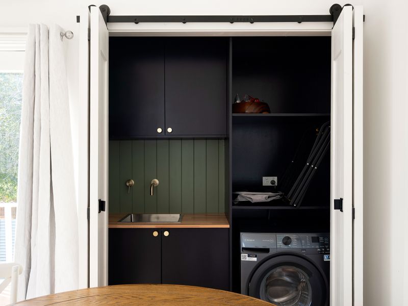 Convenient laundry cupboard featuring built-in shelving and appliances.