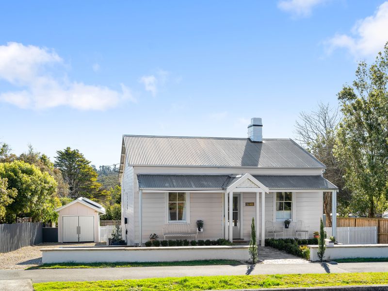 Front facade of the charming white cottage with a manicured front garden.
