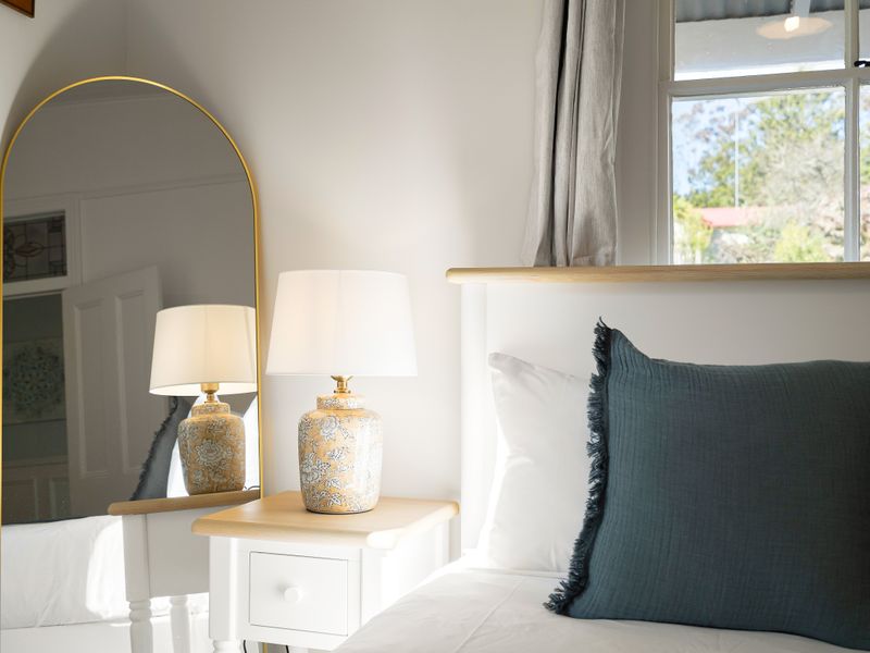 Cozy bedroom corner featuring a stylish arch mirror and warm lighting.
