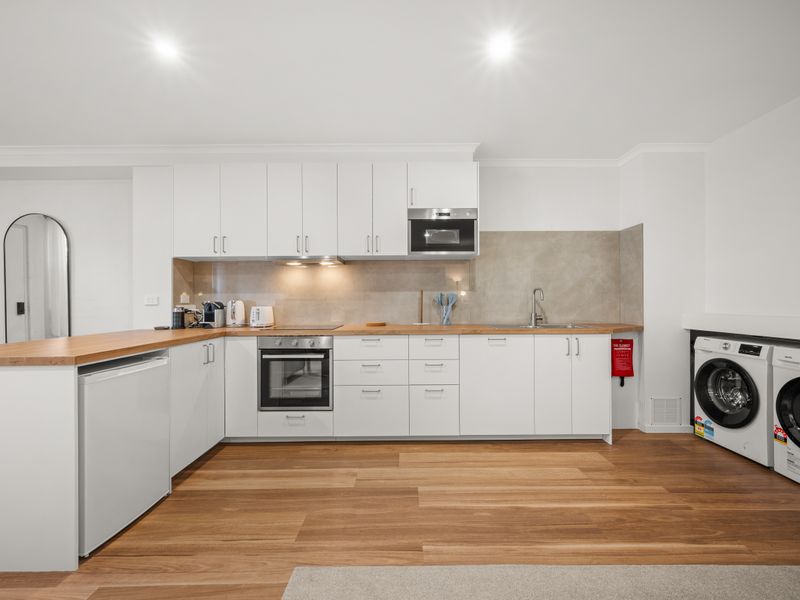 Sleek, modern kitchen featuring white cabinetry and built-in laundry appliances.