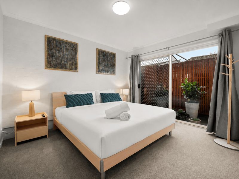 Bright bedroom with sliding glass doors opening to natural light and outdoor views